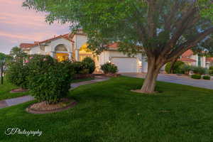 Mediterranean / spanish house featuring stucco siding, a tiled roof, concrete driveway, a garage, and a front yard