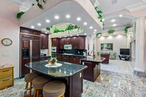 Kitchen featuring decorative columns, white microwave, crown molding, a kitchen bar, and a sink