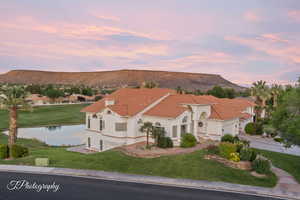 Mediterranean / spanish-style house with a water and mountain view, a front lawn, a garage, and stucco siding
