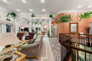 Living area featuring ornate columns, ornamental molding, and recessed lighting