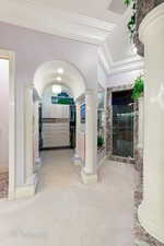Foyer with light colored carpet, ornate columns, a premium fireplace, ornamental molding, and baseboards