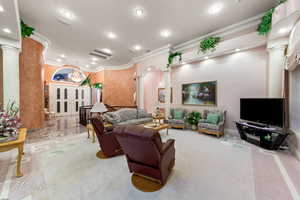 Living room featuring decorative columns, recessed lighting, ornamental molding, and arched walkways