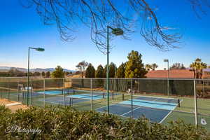 View of tennis court featuring a mountain view and fence