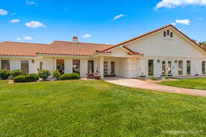 View of front of home featuring french doors, a tiled roof, a chimney, and a front yard