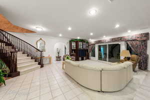 Living room featuring arched walkways, stairs, ornamental molding, and recessed lighting