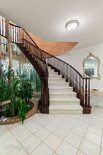 Staircase featuring tile patterned floors and ornamental molding