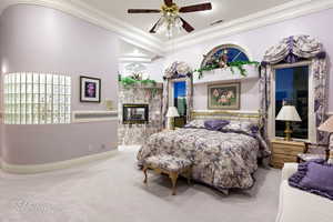 Carpeted bedroom with crown molding, a fireplace, baseboards, and ceiling fan