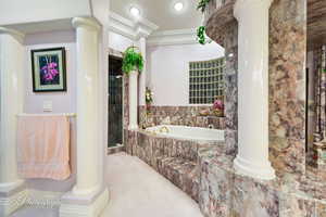 Bathroom with ornamental molding, a bath, a stall shower, and decorative columns
