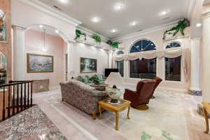Living room with decorative columns, recessed lighting, crown molding, carpet flooring, and baseboards