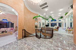 Dining room featuring arched walkways, ornamental molding, ceiling fan, baseboards, and a chandelier