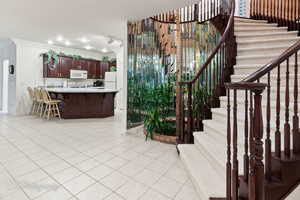 Kitchen featuring white microwave, ornamental molding, light countertops, a kitchen breakfast bar, and light tile patterned floors