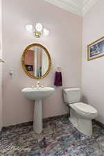 Half bath featuring toilet and ornamental molding