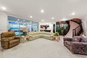 Carpeted living room with ornamental molding, stairway, and recessed lighting