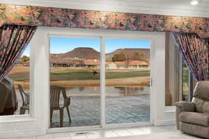 Doorway to outside with ornamental molding, a water and mountain view, and tile patterned floors