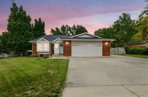 Ranch-style house featuring concrete driveway, an attached garage, and brick siding