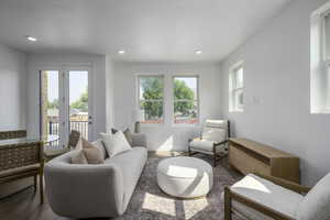 Living room with plenty of natural light, wood finished floors, and recessed lighting