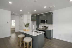 Kitchen with stainless steel appliances, a sink, baseboards, dark wood-type flooring, and backsplash