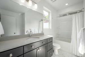 Bathroom with toilet, vanity, tile patterned flooring, and shower / bathtub combination with curtain