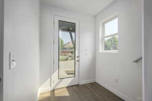 Doorway with dark wood-type flooring and baseboards
