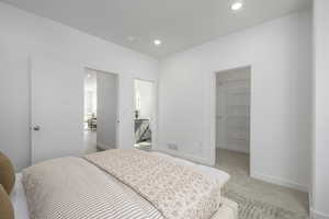 Bedroom with a spacious closet, baseboards, light colored carpet, recessed lighting, and a closet