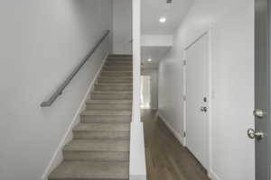 Stairs with wood finished floors, recessed lighting, and baseboards