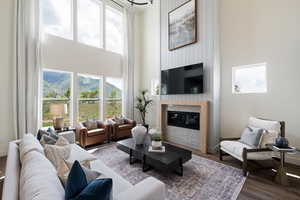 Living room with a high ceiling, a large fireplace, wood finished floors, and baseboards