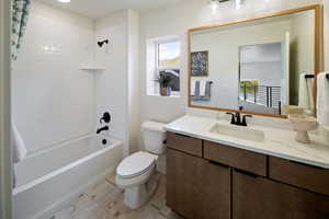 Bathroom with healthy amount of natural light, toilet, shower / bath combination with curtain, and vanity