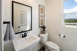 Half bath with toilet, a sink, and baseboards