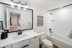 Ensuite bathroom featuring toilet, vanity, wood finished floors, and tub / shower combination