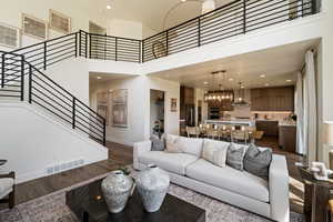 Living room with dark wood-style floors, stairs, baseboards, a high ceiling, and recessed lighting