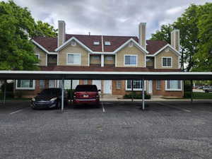 Rear view of property featuring brick siding, a chimney, and covered parking