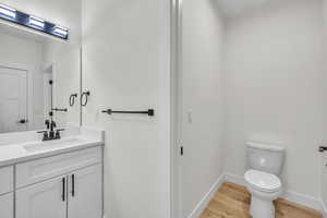 Master Bathroom with baseboards, wood finished floors, toilet, and vanity