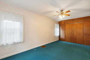 Unfurnished bedroom featuring dark colored carpet, baseboards, a closet, and a ceiling fan