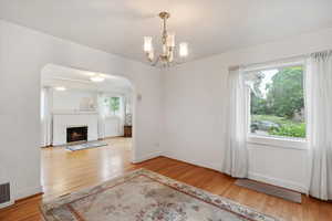 Unfurnished living room with wood finished floors, a chandelier, a fireplace, and baseboards