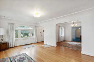 Entrance foyer featuring arched walkways, wood finished floors, a chandelier, and baseboards