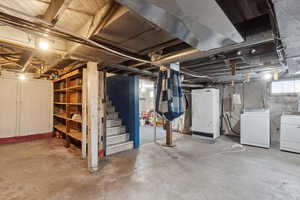 Basement featuring washing machine and clothes dryer and stairway
