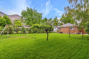 View of grassy yard featuring a playground and a mountain view