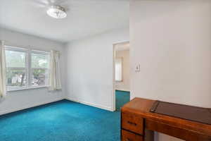 Empty room featuring dark carpet and baseboards