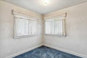 Spare room with dark carpet and baseboards
