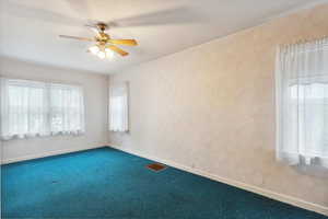 Spare room featuring carpet floors, a ceiling fan, and baseboards