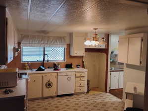 Kitchen with white appliances, a sink, light countertops, a chandelier, and hanging light fixtures