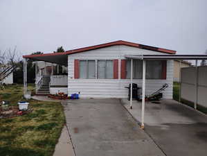 Manufactured / mobile home with concrete driveway and a front yard