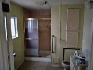 Full bath featuring a shower stall, tile patterned flooring, and toilet