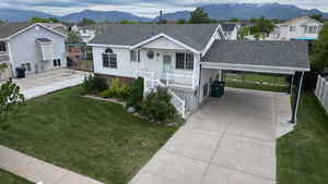 Ranch-style home featuring a carport, roof with shingles, concrete driveway, a mountain view, and a residential view