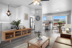 Living room with a ceiling fan, LVP, wood look finished floors, baseboards, and a textured ceiling