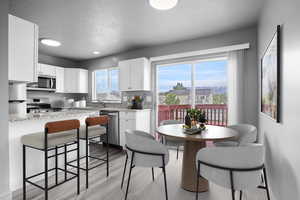 Kitchen featuring appliances with stainless steel finishes, a textured ceiling, a sink, a kitchen breakfast bar, and white cabinetry