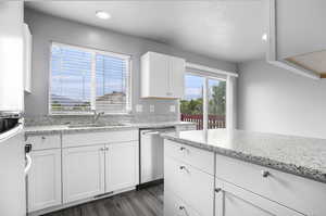 Kitchen featuring a sink, dishwasher, white cabinets, and a textured ceiling