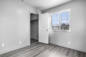 Second bedroom featuring LVP, wood look floors, baseboards, a closet, a textured ceiling, and a walk in closet