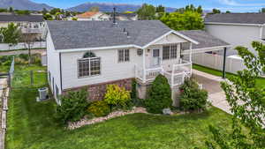 View of front facade featuring central AC unit, a shingled roof, and a mountain view