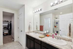 Bathroom featuring a dual sinks and a large walk in closet.